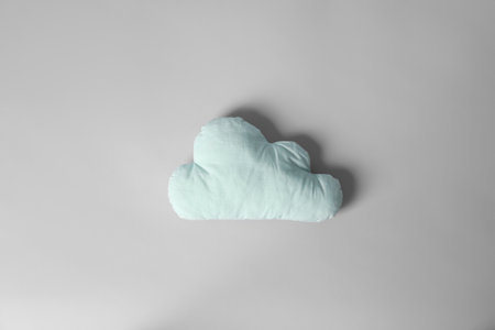 Soft pillow in shape of cloud on light backgroundの写真素材