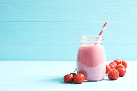 Glass jar with tasty strawberry smoothie on tableの写真素材