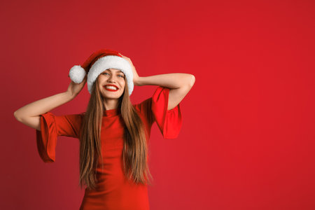 Young beautiful woman in Santa hat on color background. christmas celebrationの写真素材