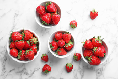 Bowls with ripe red strawberries on marble background, top viewの写真素材