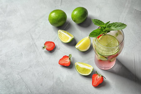 Natural lemonade with lime and strawberries in glass on light backgroundの写真素材