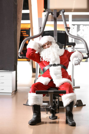 Authentic Santa Claus resting after exercise in modern gymの写真素材