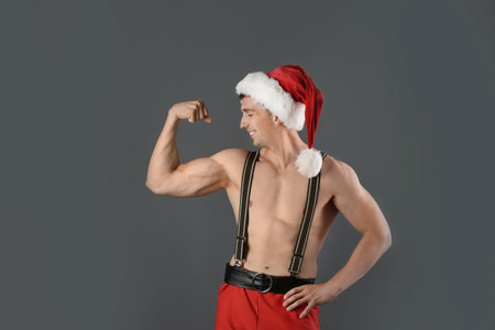 Young muscular man in Santa hat on gray backgroundの写真素材