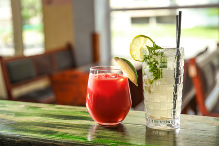 Glasses of delicious cocktails with ice on table