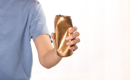 Woman holding crumpled aluminum can on blurred background. metal waste recycling