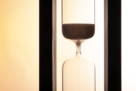 Hourglass with flowing sand on light background. time managementの写真素材