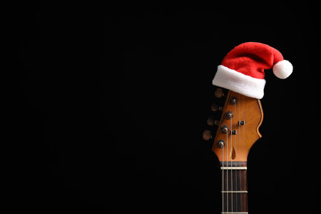 Guitar with Santa hat on black background. christmas music conceptの写真素材