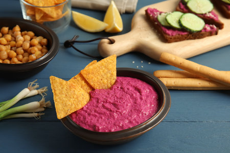 Bowl of tasty beet hummus and chips on wooden tableの写真素材