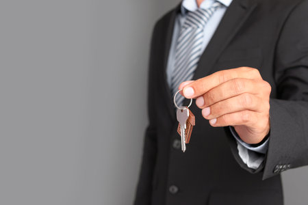 Real estate agent with key on gray backgroundの写真素材