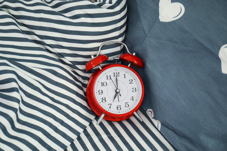 Analog alarm clock on bed, top view. Time of dayの写真素材