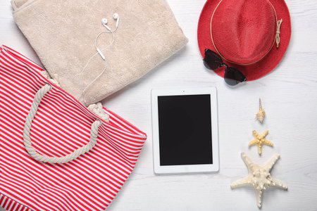 Flat lay composition with tablet and beach objects on wooden background
