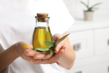 Young woman holding bottle of fresh olive oil, closeupの写真素材