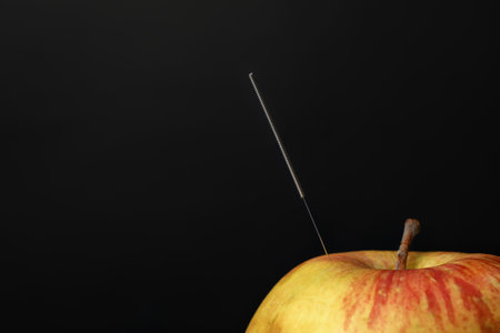 Needle for acupuncture and apple on dark backgroundの写真素材