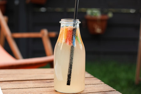 Bottle of tasty lemonade on wooden table