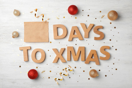 Flat lay composition with words DAYS TO XMAS and holiday decor on wooden background. christmas count...