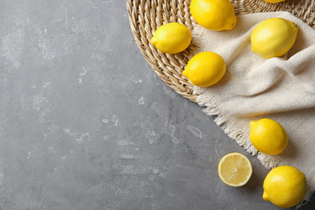 Flat lay composition with lemons, fabric and straw mat on gray backgroundの写真素材