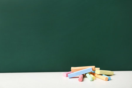 Pieces of chalk on table near boardの写真素材