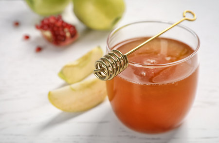 Glass of honey, apples, pomegranate and dipper on light table. Rosh Hashanah holidayの写真素材