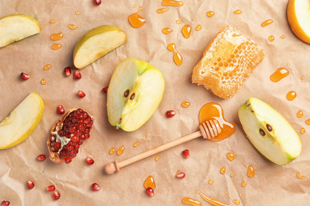 Flat lay composition with drops of honey, dipper, sliced apples and pomegranate on parchment paper. Rosh Hashanah holidayの写真素材