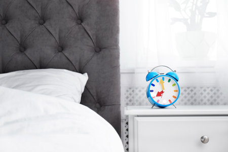 Analog alarm clock on table in bedroom. Time of dayの写真素材