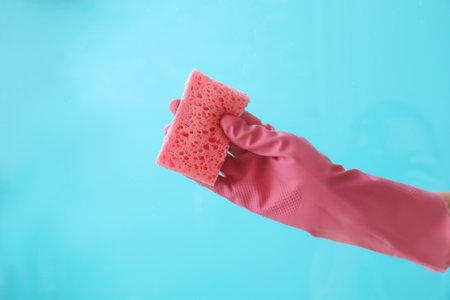 Woman cleaning glass against color backgroundの写真素材