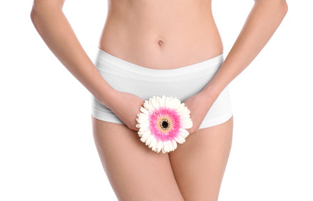 Young woman holding flower near underwear on white background. Gynecologyの写真素材