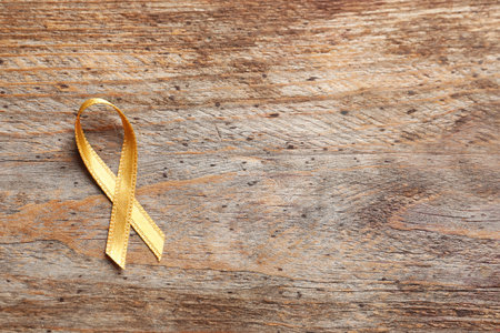 Gold ribbon on wooden background, top view. cancer awarenessの写真素材