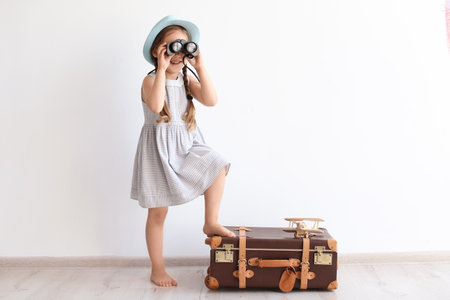 Adorable little child playing traveler with suitcase indoorsの写真素材