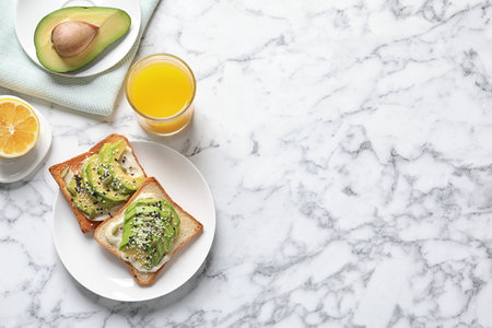 Flat lay composition with toast bread, avocado and glass of juice on marble background