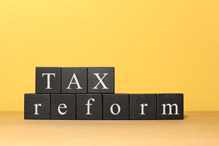 Black cubes on table against color background. tax conceptの写真素材