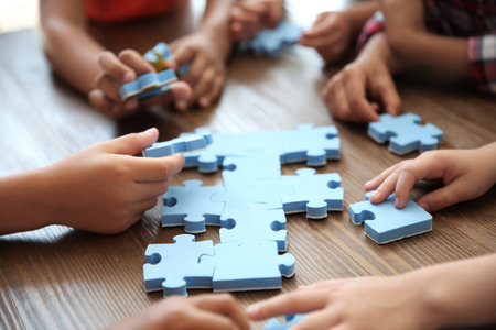 Little children playing with puzzle at table, focus on hands. unity conceptの写真素材