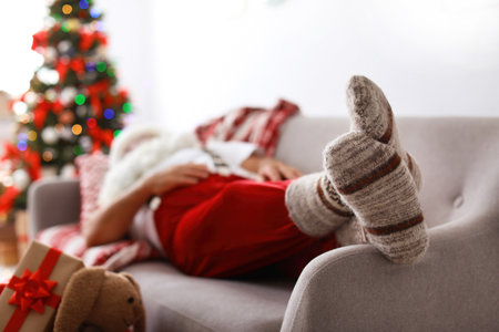 Authentic Santa Claus in warm socks sleeping on sofa indoorsの写真素材