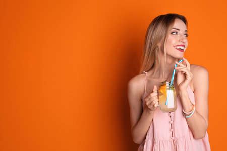 Young woman with mason jar of tasty lemonade on color background. natural detox drinkの写真素材