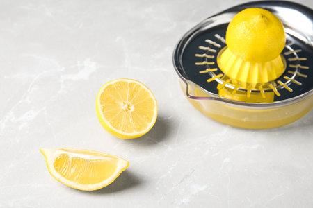 Slices of lemon and juicer on gray table