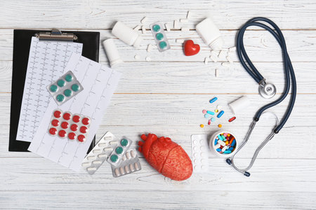Flat lay composition with stethoscope and pills on wooden background. Cardiology serviceの写真素材