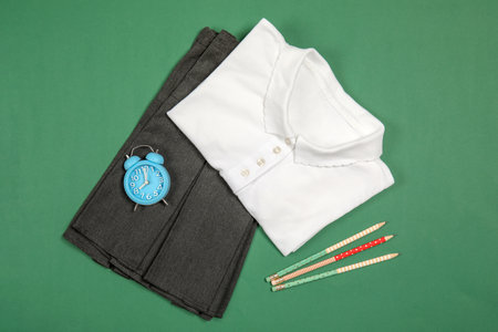 School uniform for girl and alarm clock on color background, top viewの写真素材
