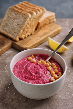 Bowl with fresh beet hummus, slices of bread and lemon on tableの写真素材