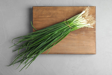 Fresh green onion on wooden board, top viewの写真素材