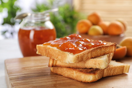 Bread with tasty apricot jam on wooden boardの写真素材