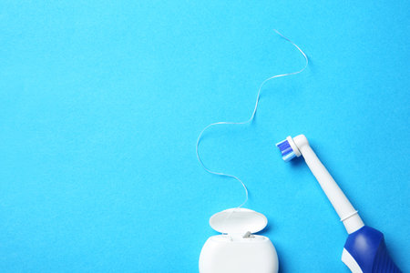 Flat lay composition with electric toothbrush and dental floss on color backgroundの写真素材