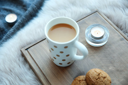Burning candles, cup of coffee and cookies on wooden boardの写真素材