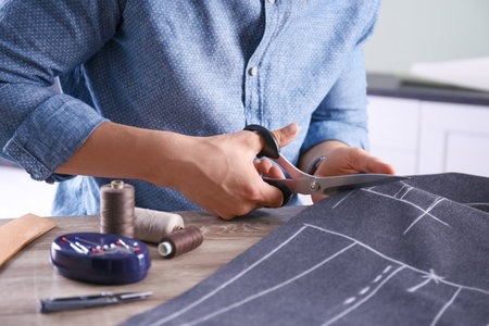 Tailor cutting fabric at table in atelier, closeupの写真素材