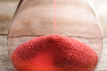 Hourglass with flowing sand on table, closeup. time management