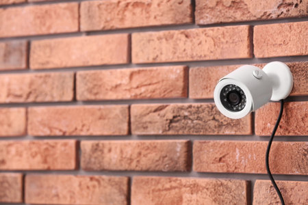 Modern security CCTV camera on brick wall