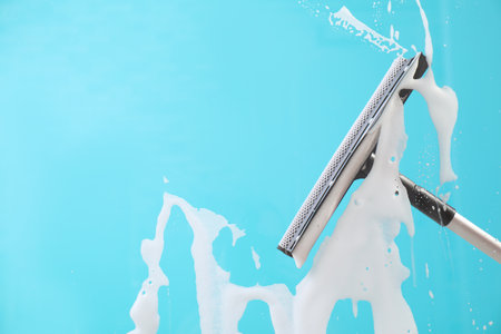 Cleaning glass with squeegee on color backgroundの写真素材