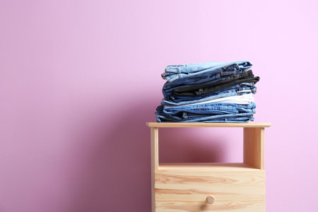 Stack of different jeans on table against color backgroundの写真素材