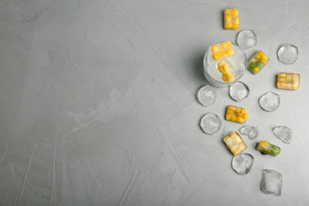 Frozen vegetables and ice cubes on gray background, flat lay composition with space for textの写真素材