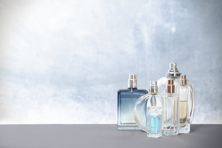 Different perfume bottles on table against color background