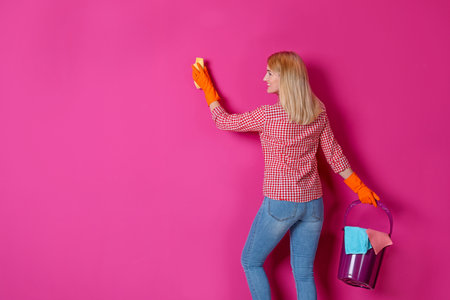 Woman in gloves cleaning color wall with ragの写真素材