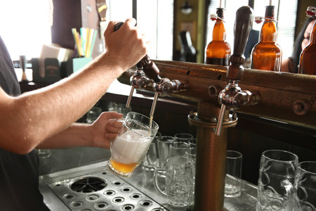 Bartender pouring beer from tap into glass in bar, closeupの写真素材